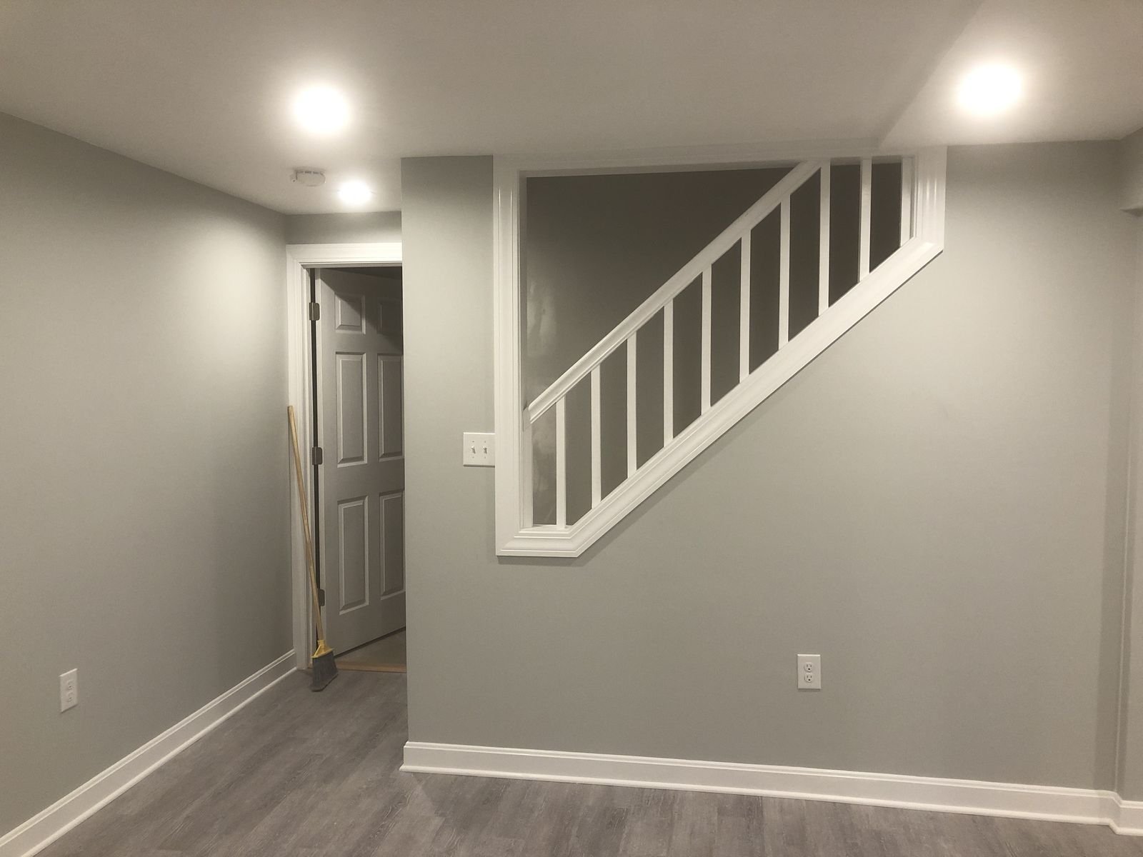 Finished basement with white staircase and railing