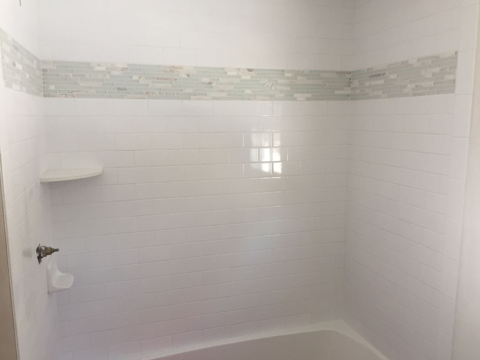 Tub surround in white tile with a glass mosaic band